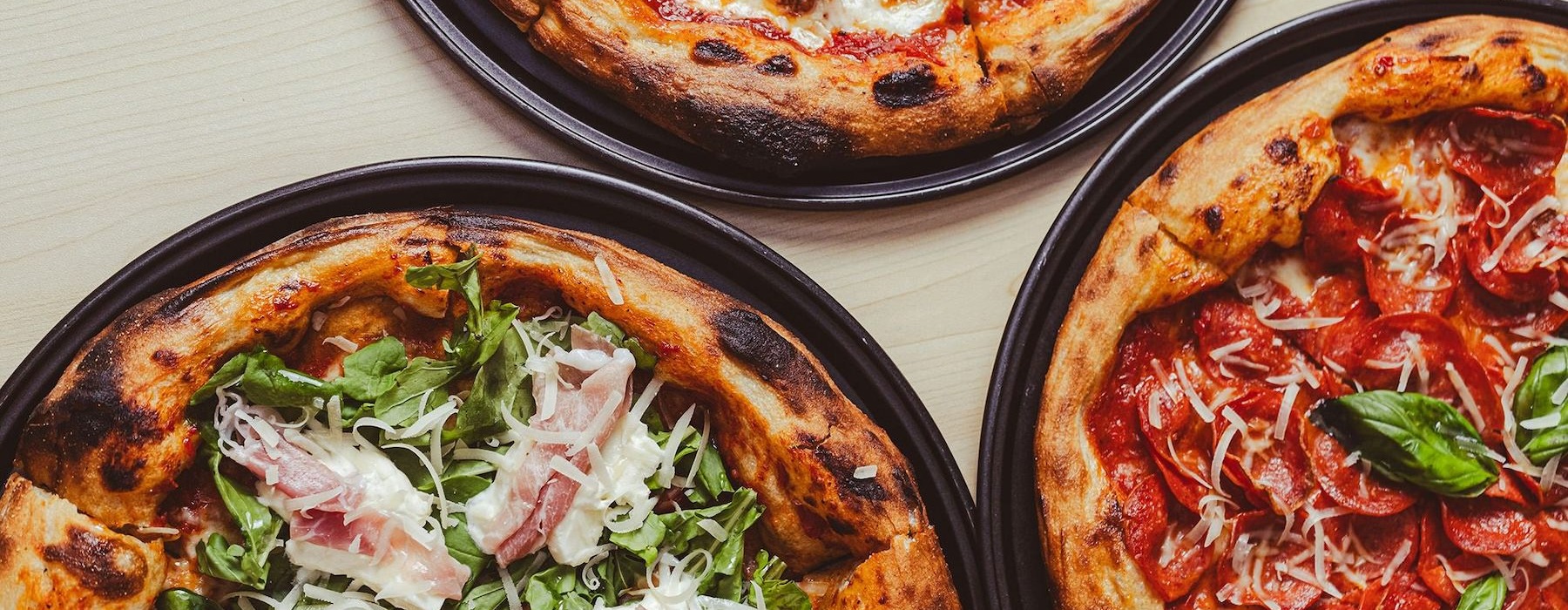 Three pizzas with toppings on them.